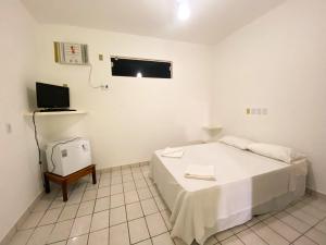 um quarto branco com uma cama e uma televisão em POUSADA PRAIAMAR em Prado