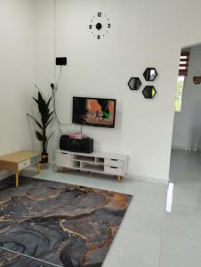 a living room with a tv on a white wall at Homestay Berkat D'sawah Tasek Berangan Pasir Mas in Pasir Mas