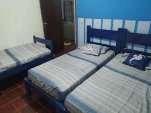 two twin beds in a room with blue walls at RAIO DE LUZ GUARAPARI BEACH in Guarapari