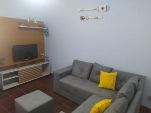 a living room with a gray couch and yellow pillows at RAIO DE LUZ GUARAPARI BEACH in Guarapari