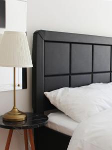 a bed with a black headboard and a table with a lamp at Lev Florentin Apartments in Tel Aviv