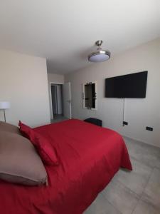 1 dormitorio con cama roja y TV de pantalla plana en Arecas en Villa Carlos Paz