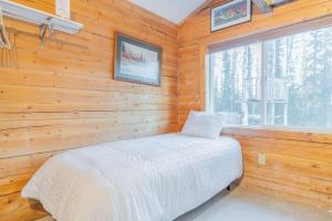 a bedroom with a bed in a wooden wall at Private Cabin With Alaskan Charm in Fairbanks