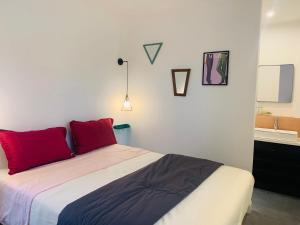 a bedroom with a bed with red pillows and a sink at La muche 2 in Marquillies