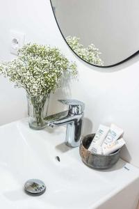 lavabo con espejo y jarrón de flores en Apartamento Bguest con terraza en Alicante