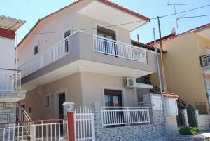 a large house with white balconies and a fence at Marianna Apartments in Nea Roda
