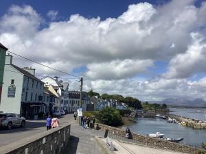 a group of people walking down a street next to a river at Roundstone Harbour lights Roundstoneselfcatering in Roundstone