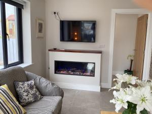 a living room with a fireplace with a tv above it at Roundstone Harbour lights Roundstoneselfcatering in Roundstone