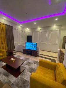 a living room with a yellow couch and a tv at شاليهات ركـــام Recam For Holiday in Qarār