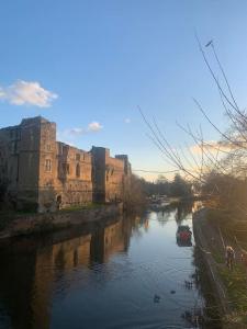 a river in front of a castle with a building at Unique Central Newark Double-Height Apartment in Newark-on-Trent