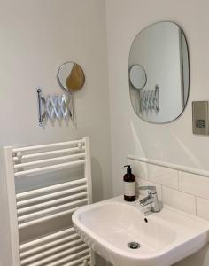 a white bathroom with a sink and a mirror at Unique Central Newark Double-Height Apartment in Newark upon Trent