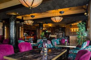 um restaurante com cadeiras roxas, uma mesa e um bar em Holyrood Hotel - Leisure Centre & The Spa at Orchids em Bundoran