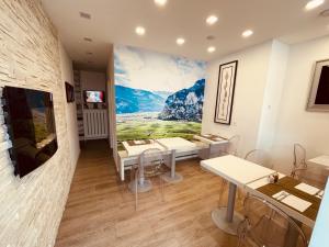 een kamer met tafels en stoelen en een muurschildering aan de muur bij Casa da Carmen Boutique & Private Spa in Mezzolombardo