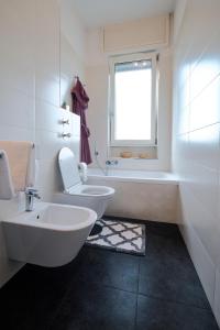 uma casa de banho com um lavatório, um WC e uma janela. em San Siro Design Apartment em Milão