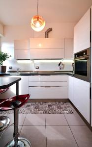 una cucina con armadi bianchi e uno sgabello rosso di San Siro Design Apartment a Milano