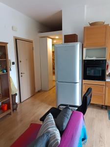 a kitchen with a refrigerator and a person sitting on a couch at BOLOGNA QUARTIERE SAVENA - APPARTAMENTO DI STEFANO in Bologna