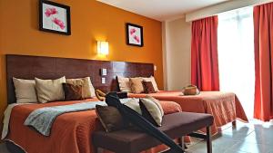 um quarto de hotel com duas camas e uma cadeira em Posada Del Carmen Aguascalientes em Aguascalientes