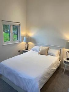 a bedroom with a large white bed with two lamps at The Lodge in Royal Tunbridge Wells