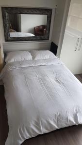 a white bed in a bedroom with a mirror at Beautiful holiday studio in the heart of Rochester in Rochester