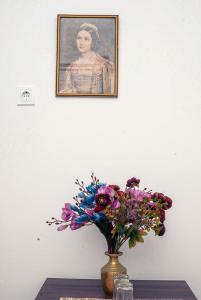 a vase with flowers on a table in front of a painting at Residencial Airside Palace in Lisbon