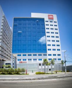 a tall blue building with a person walking in front of it at NB Hoteis in Aracaju