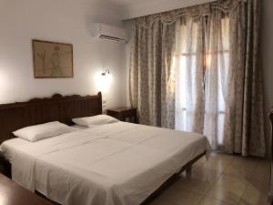 a bedroom with a large white bed and a window at Villa Christina Skiathos in Vromolimnos