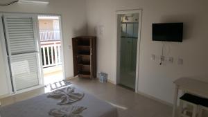 a living room with a shower and a television at Pousada Peruíbe Ametista in Peruíbe