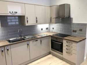 una cocina con armarios blancos y electrodomésticos de acero inoxidable en Central Newark Apartment 1 St Mary’s Rooms, en Newark-on-Trent
