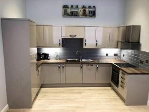 a kitchen with white cabinets and a sink and stove at Central Newark Apartment 1 St Mary’s Rooms in Newark-on-Trent