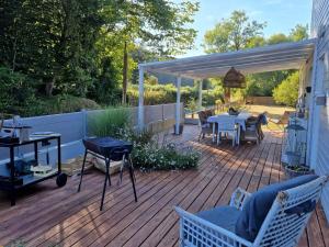 patio con tavolo e sedie su una terrazza in legno di lodge avec vue sur la rivière a Lannion