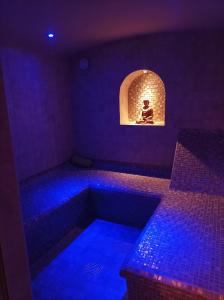 Cette chambre dispose d'une baignoire éclairée en bleu avec une personne assise. dans l'établissement Chambre d'hôte avec Hammam et salle de jeux, à Chazelles-sur-Lyon