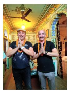 two men are holding their hands in a room at Raj Haveli- A Heritage Samode in Jaipur