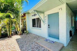 a white house with a door and a palm tree at Luxury 2/2 private oasis w/Hot Tub walk to Beach in Cape Canaveral