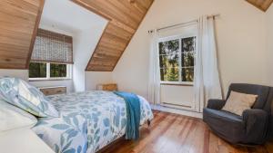 1 dormitorio con 1 cama, 1 silla y ventanas en The Carriage House en Victoria