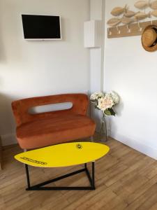 a yellow surfboard sitting in a room with a chair at Juste au dessus de la Veules in Veules-les-Roses