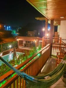 a hammock on the balcony of a resort at night at Pousada Rosa Maria in Praia do Rosa