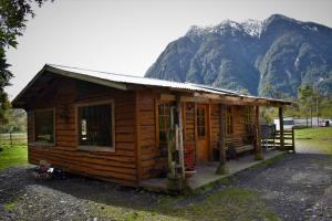 a small wooden cabin with a mountain in the background at cabañas rio yelcho in Chaitén