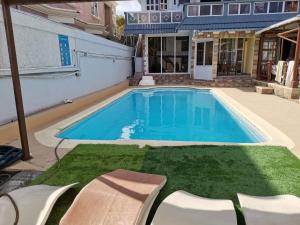 a swimming pool with chairs in front of a house at Reviva Residence in Blue Bay