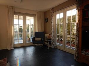 a living room with large windows and a chair at Comfortabel en gezellig vakantiehuis bij het strand in Wemeldinge