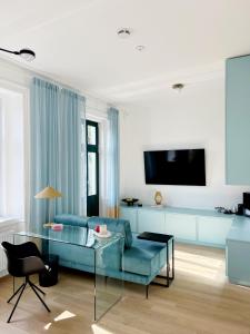 Sissi West في فيينا: غرفة معيشة مع أريكة زرقاء وتلفزيون