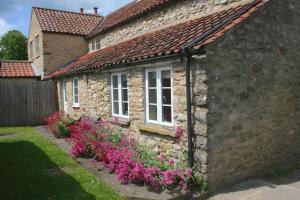 a stone house with flowers in front of it at Pretty Yorkshire Stone Cottage Harome in Harome