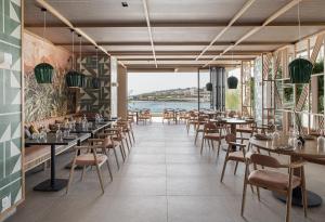 een restaurant met tafels en stoelen en uitzicht op het water bij Eden Roc Resort - All Inclusive in Kallithea Rhodes