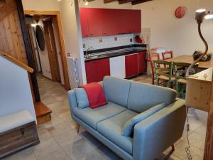 sala de estar con sofá azul y cocina en Mansarda Abetone, en Abetone
