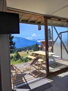 balcón con mesa y vistas a la montaña en Sorbiers A02 à Chamrousse 1700 en rez de jardin plein sud, en Chamrousse