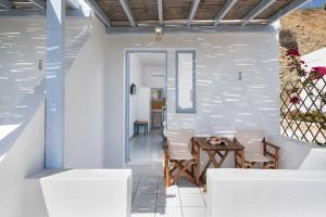 阿納菲島的住宿－TA PLAGIA accommodation，一间配备有白色椅子和桌子的用餐室