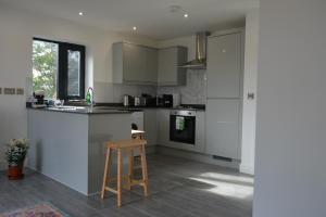 a kitchen with white cabinets and a stool in it at 8 Jarn Court in Oxford