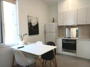 a white kitchen with a white table and chairs at Apollonas - 1BR Lux Apartment - Tsimiski Ladadika - Explore Center by foot - Close to Aristotelous square in Thessaloniki