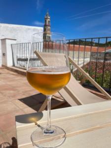 a glass of wine sitting on a ledge with a lighthouse at Balcón de la Moreria con alberca in Constantina