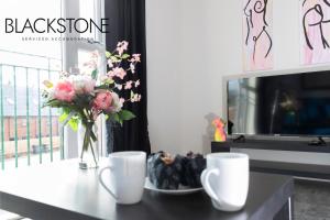 una mesa con un jarrón de flores y dos tazas en Avery House 4 - One Bedroom with Outdoor Terrace, en Darlington