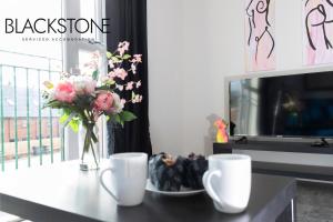a table with a vase of flowers and two cups at Avery House 4 - One Bedroom with Outdoor Terrace in Darlington